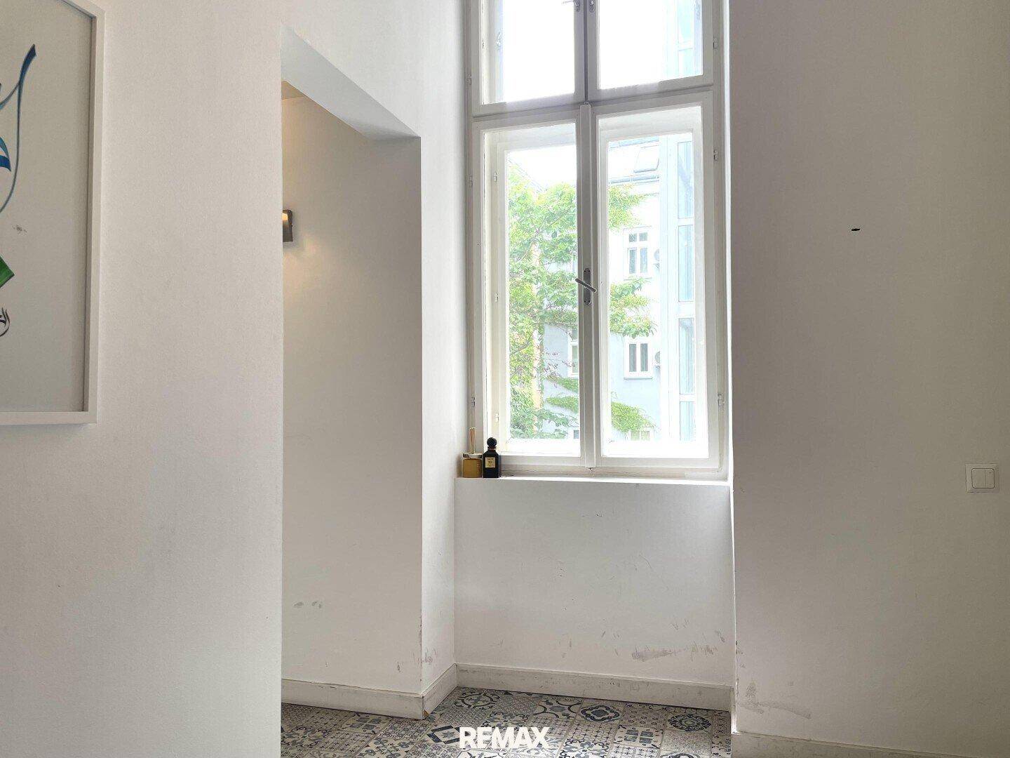 Heller Flur mit Fenster und dekorativen gemusterten Bodenfliesen, bietet Tageslicht.