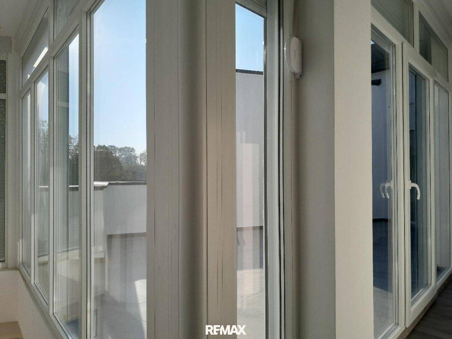 Heller Wintergarten mit großen Fensterfronten, die viel Tageslicht hereinlassen und eine weite Aussicht bieten.