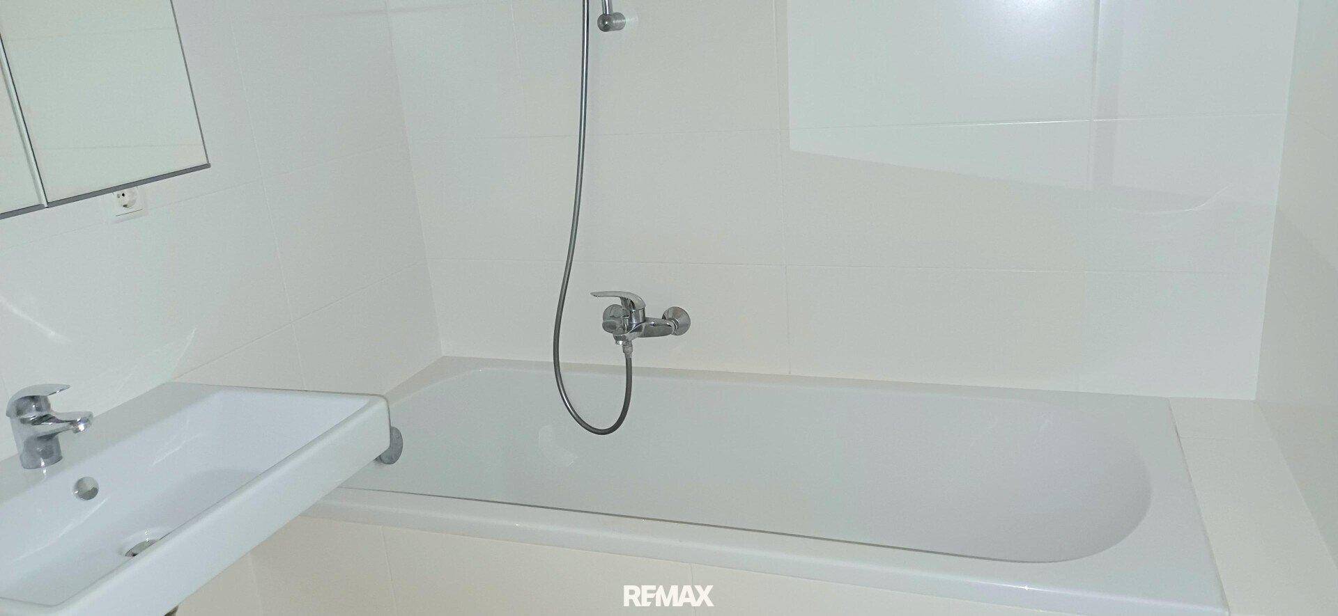 Badezimmer mit weißer Badewanne und Waschbecken, komplett gefliest in hellem, funktionalem Design.