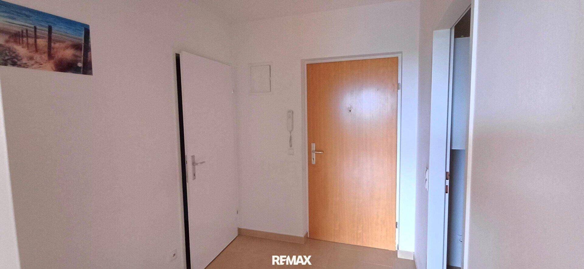 Eingangsbereich mit Holztür und weißen Innentüren, bietet Zugang zu den verschiedenen Wohnräumen.