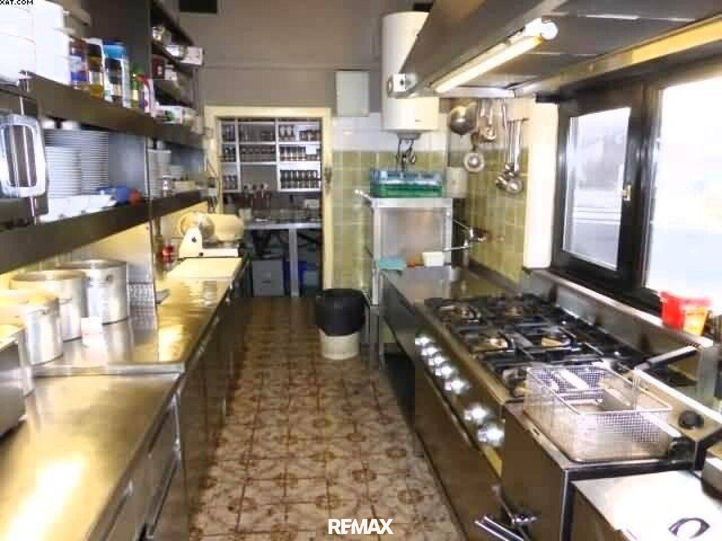 Professionelle Küche mit Edelstahlgeräten, Gasherd und gefliestem Boden, ideal für Gastronomiebetriebe.