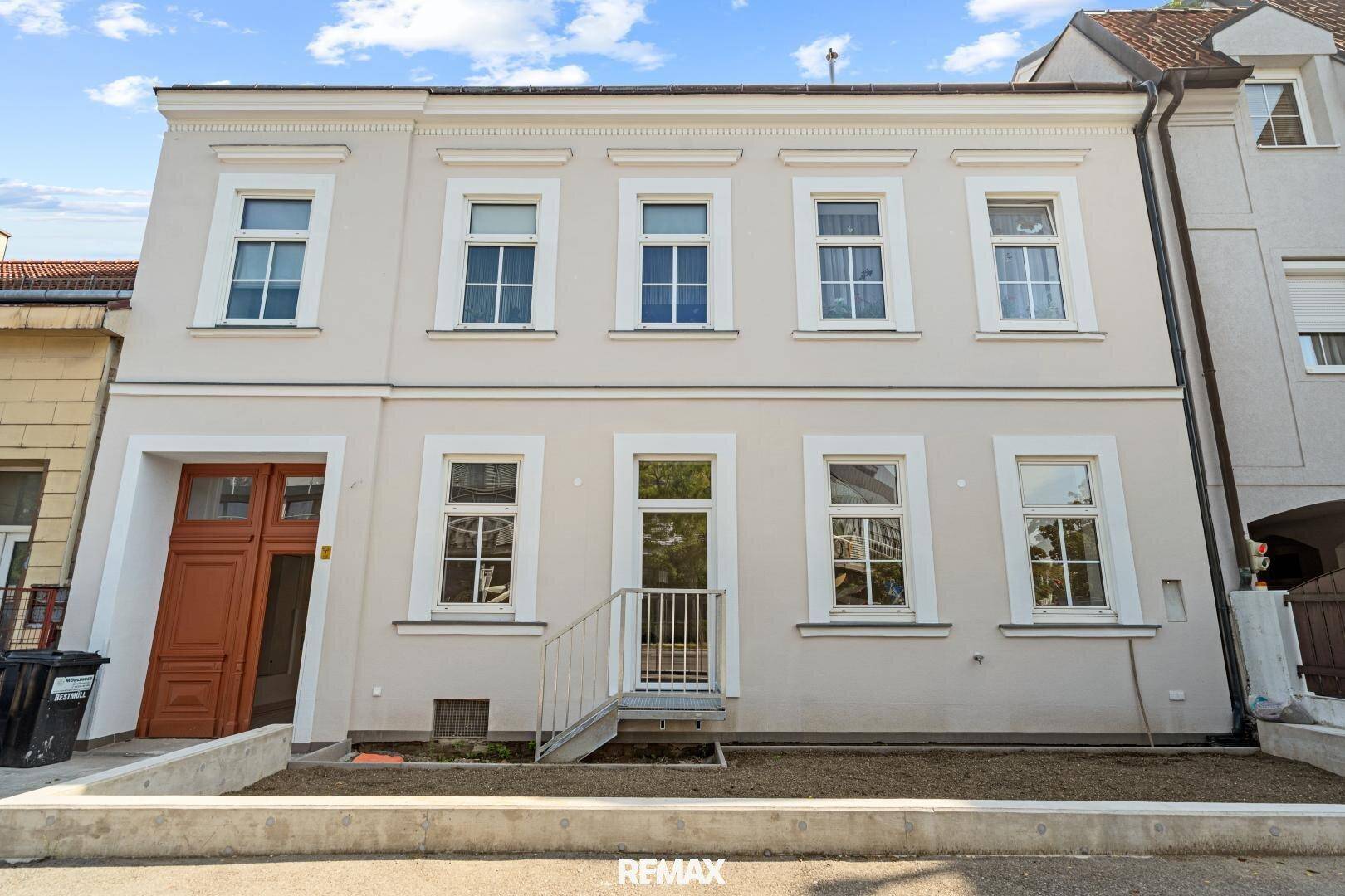 Vorderansicht des Gebäudes mit klassischer Fassade, großen Fenstern und dem Haupteingang.