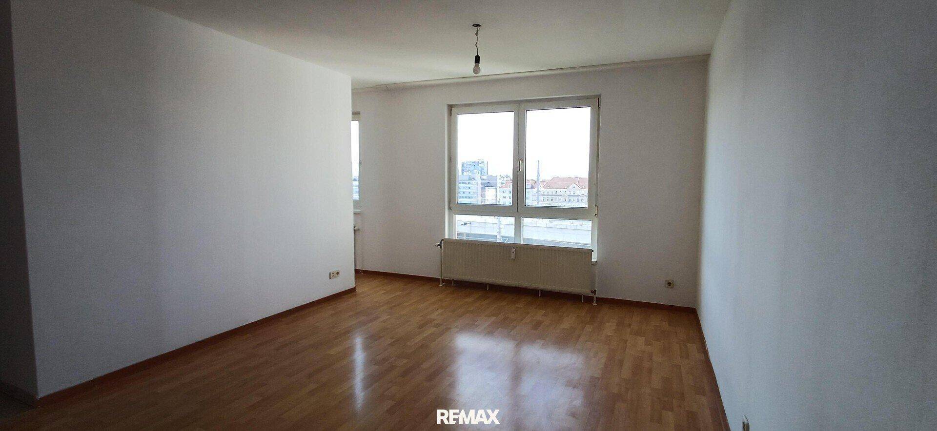 Heller, leerer Raum mit Holzparkettboden und großem Fenster, bereit zur individuellen Gestaltung.