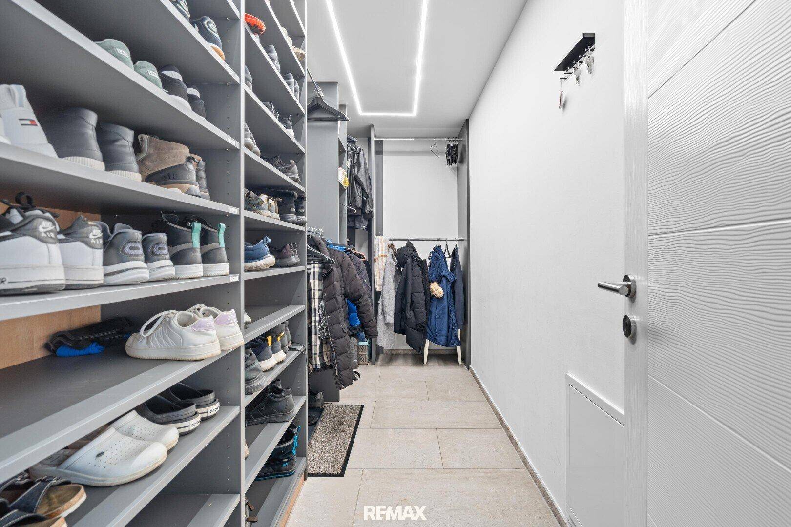Geräumiger begehbarer Kleiderschrank mit zahlreichen Regalen für Schuhe und Kleidung.