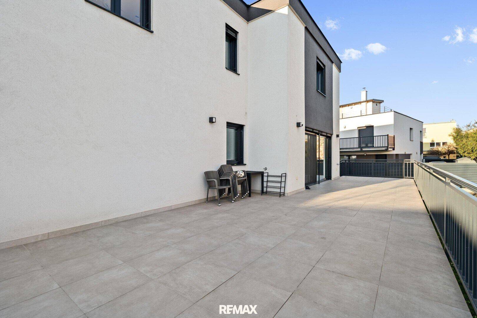 Große geflieste Terrasse neben dem Haus, ideal für Entspannung und Mahlzeiten im Freien.