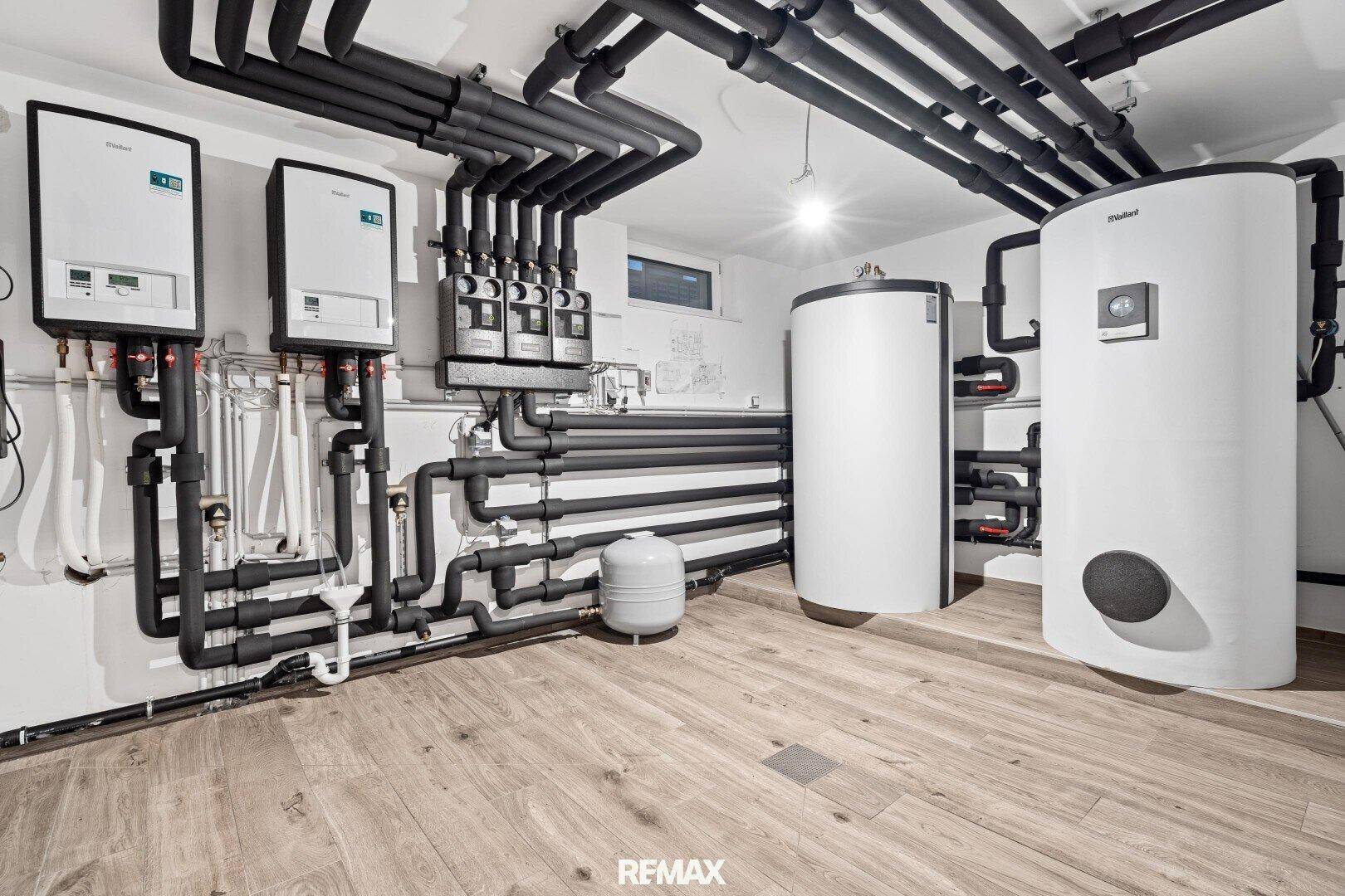 Technikraum mit modernen Heizungsanlagen, Warmwasserspeichern und gut isolierten Rohren.