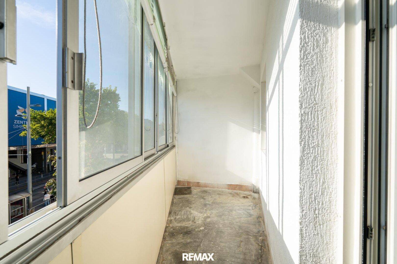 Verglaster Balkon mit Blick auf die Stadt und viel Sonnenlicht, ideal zum Entspannen.