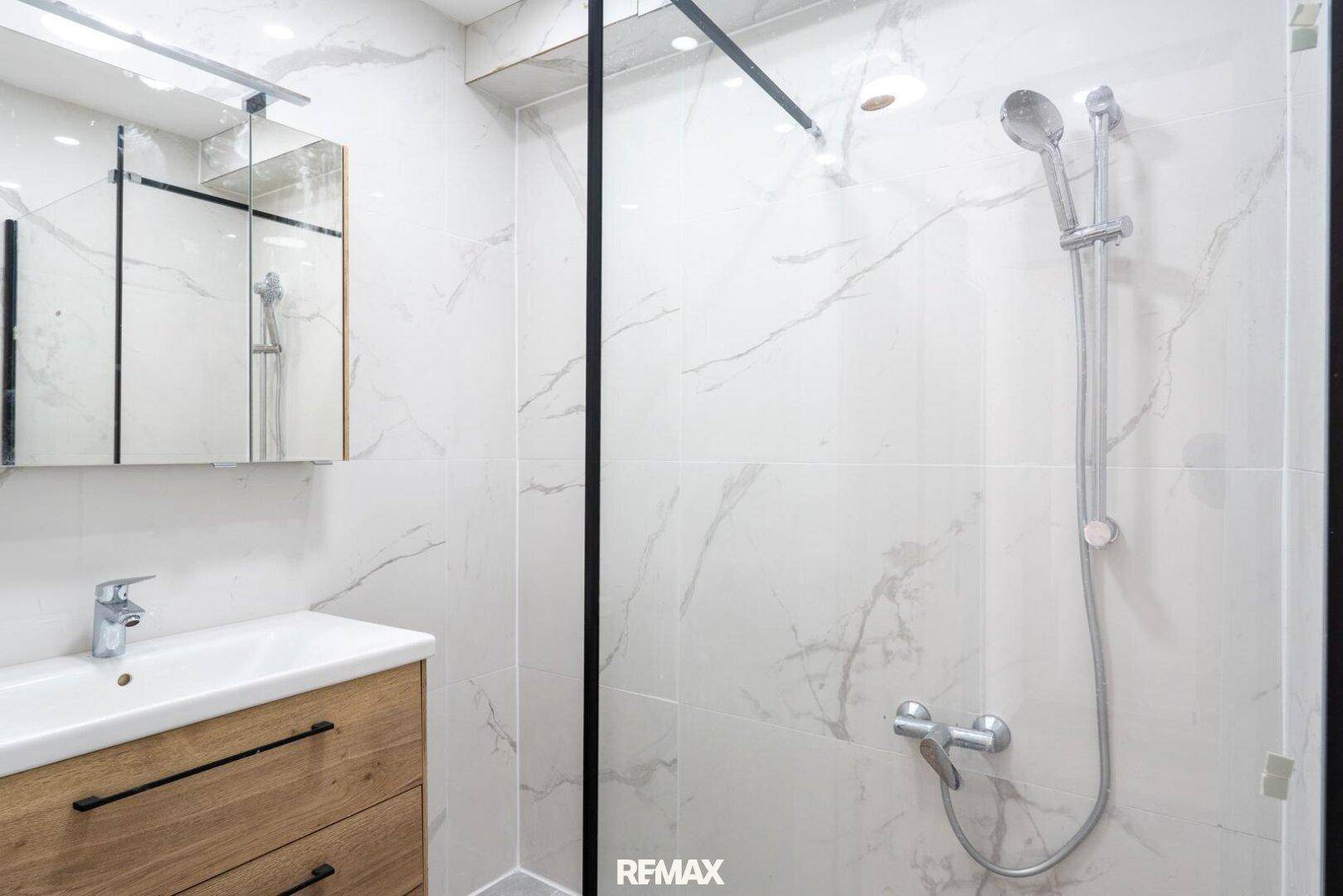 Modernes Badezimmer mit begehbarer Dusche, Marmorfliesen und einem Einzelwaschbecken mit Unterschrank.