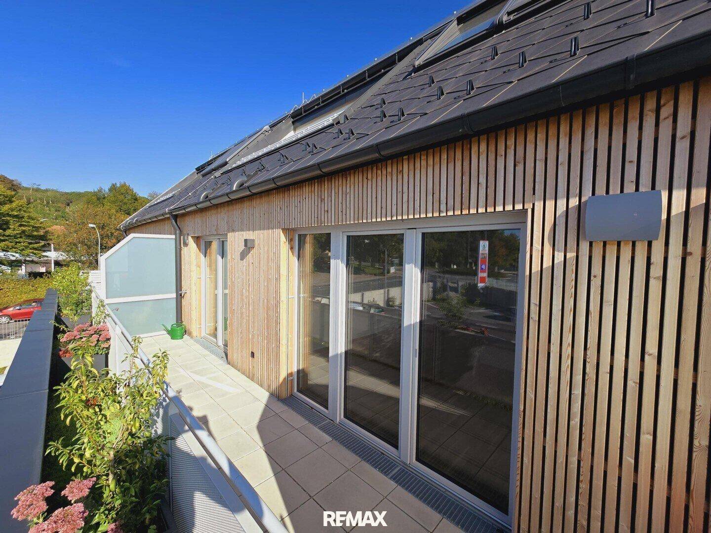 Moderne Gebäudefassade mit Holzverkleidung und großen Fenstern.