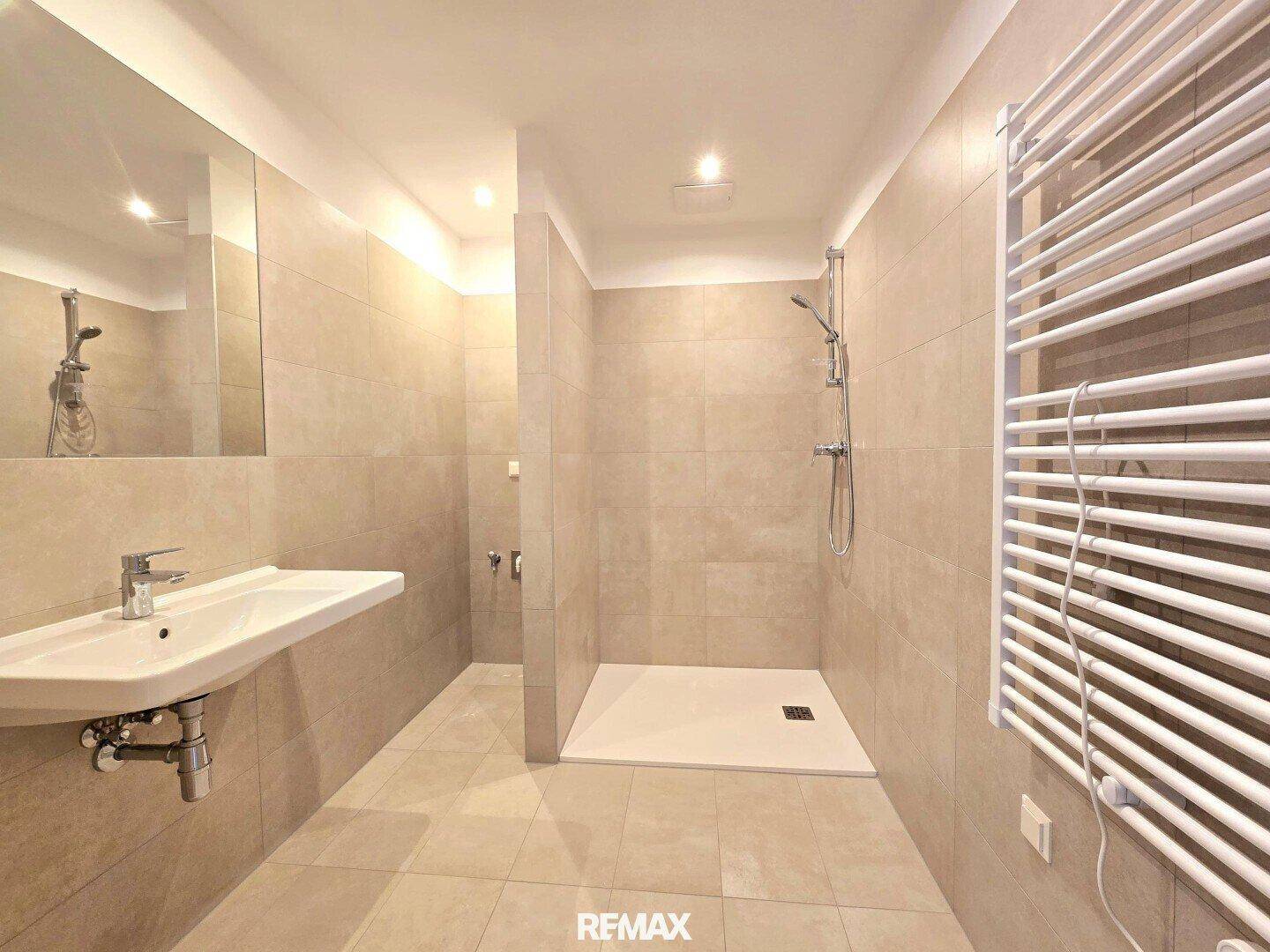 Modernes Badezimmer mit begehbarer Dusche, beigefarbenen Fliesen und Handtuchheizkörper.