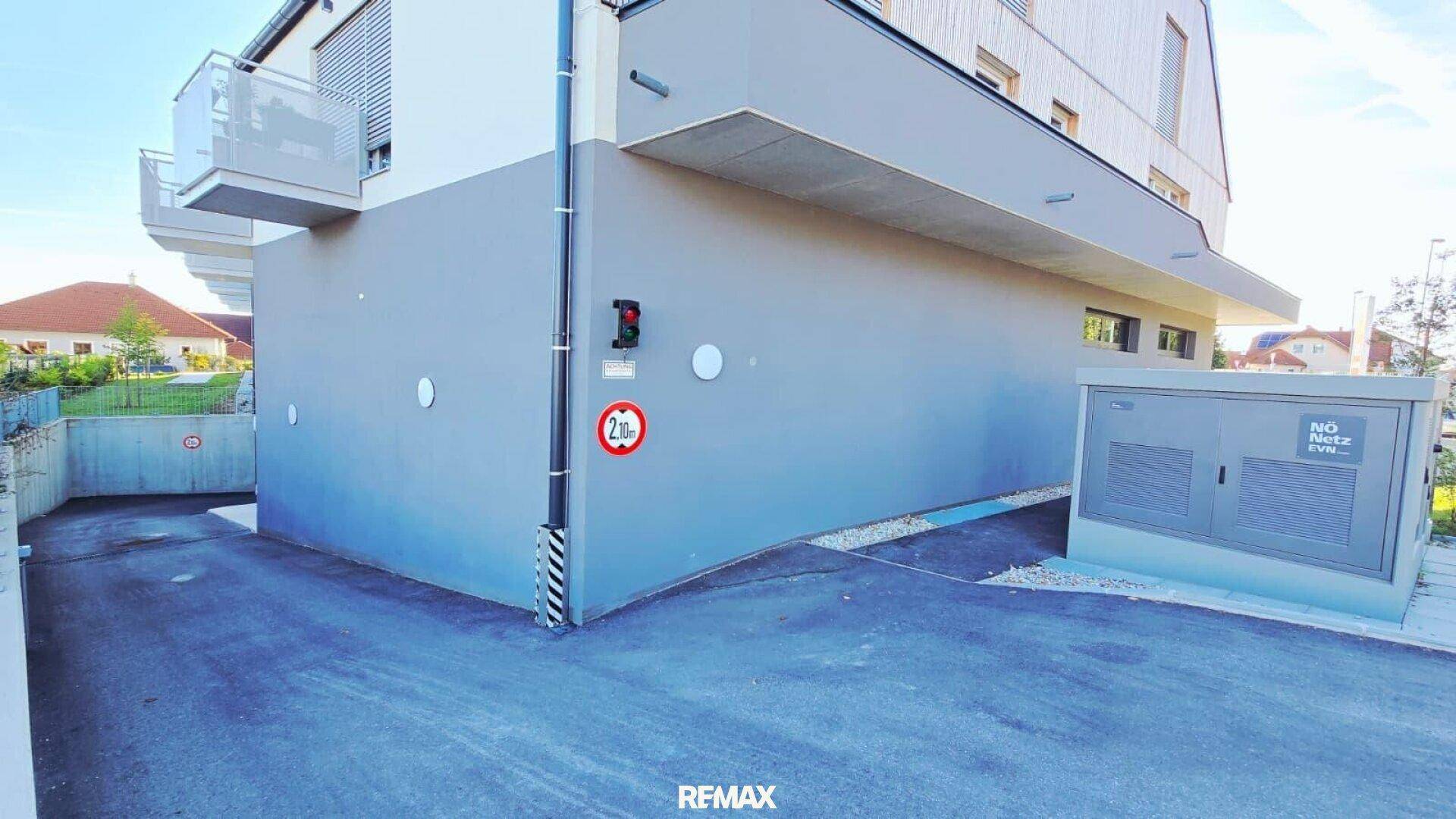 Zufahrt zur Tiefgarage des modernen Gebäudes mit grauer Fassade.