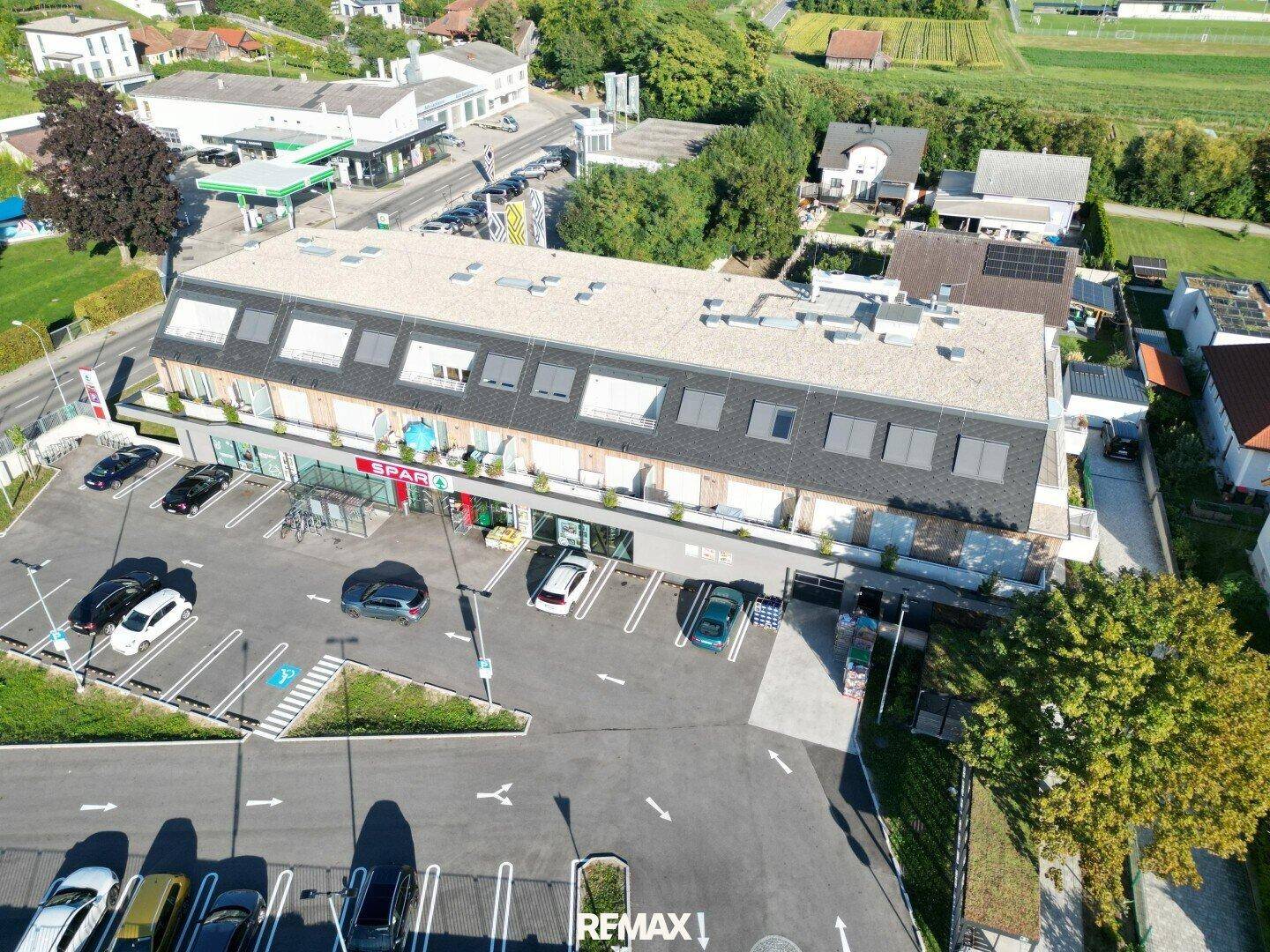 Luftaufnahme des modernen Gebäudes mit Parkplätzen und umliegender Landschaft.