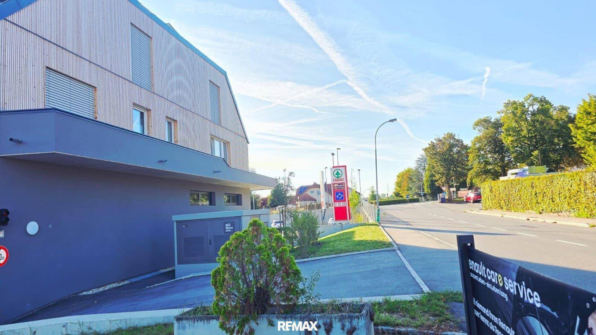 Seitenansicht des modernen Gebäudes mit Tiefgaragenzufahrt und Straße.