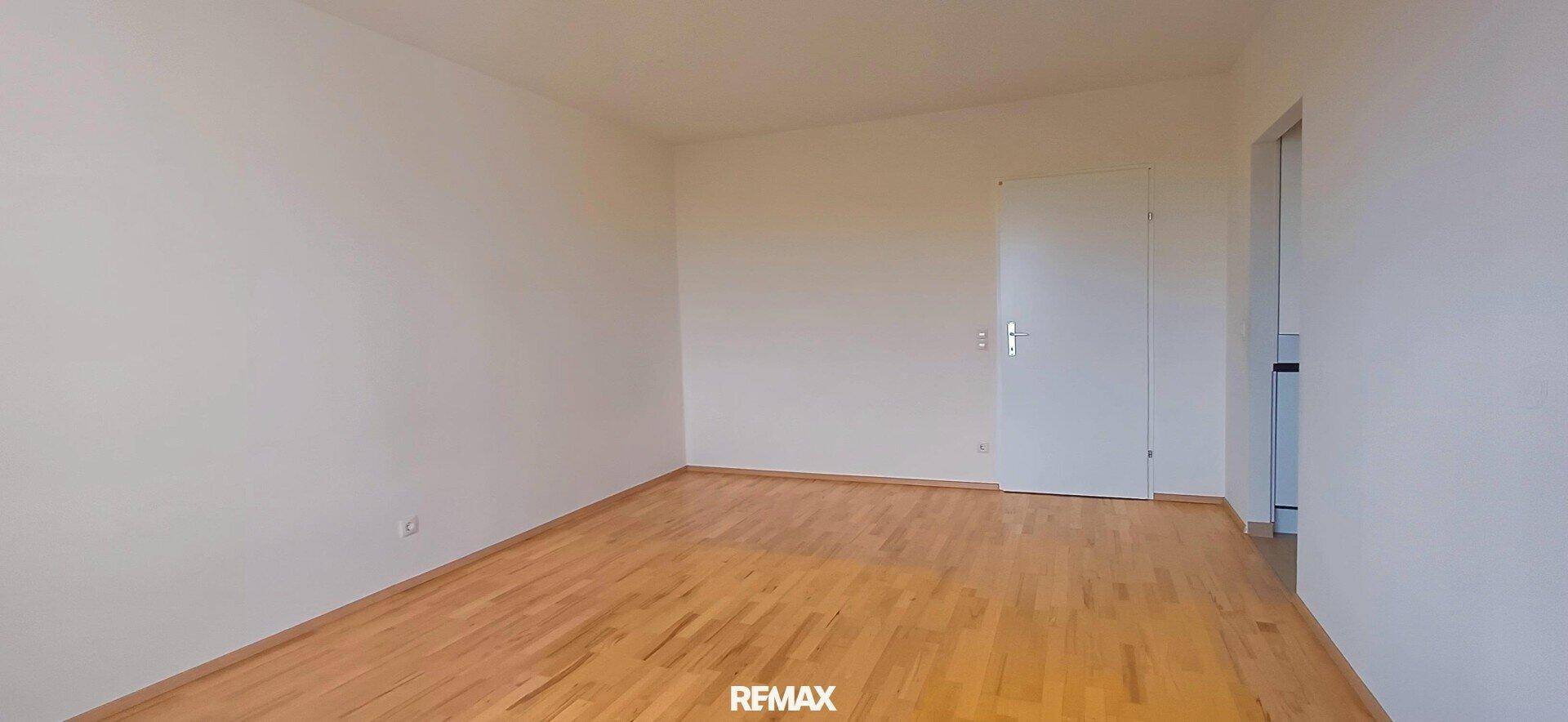 Geräumiges Zimmer mit hellem Holzboden und weißer Tür, bereit zur individuellen Gestaltung.