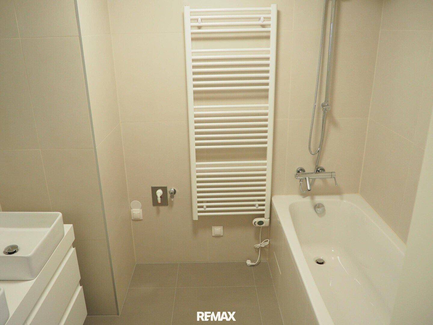 Helles Badezimmer mit Badewanne, modernem Waschbecken und beheiztem Handtuchhalter.
