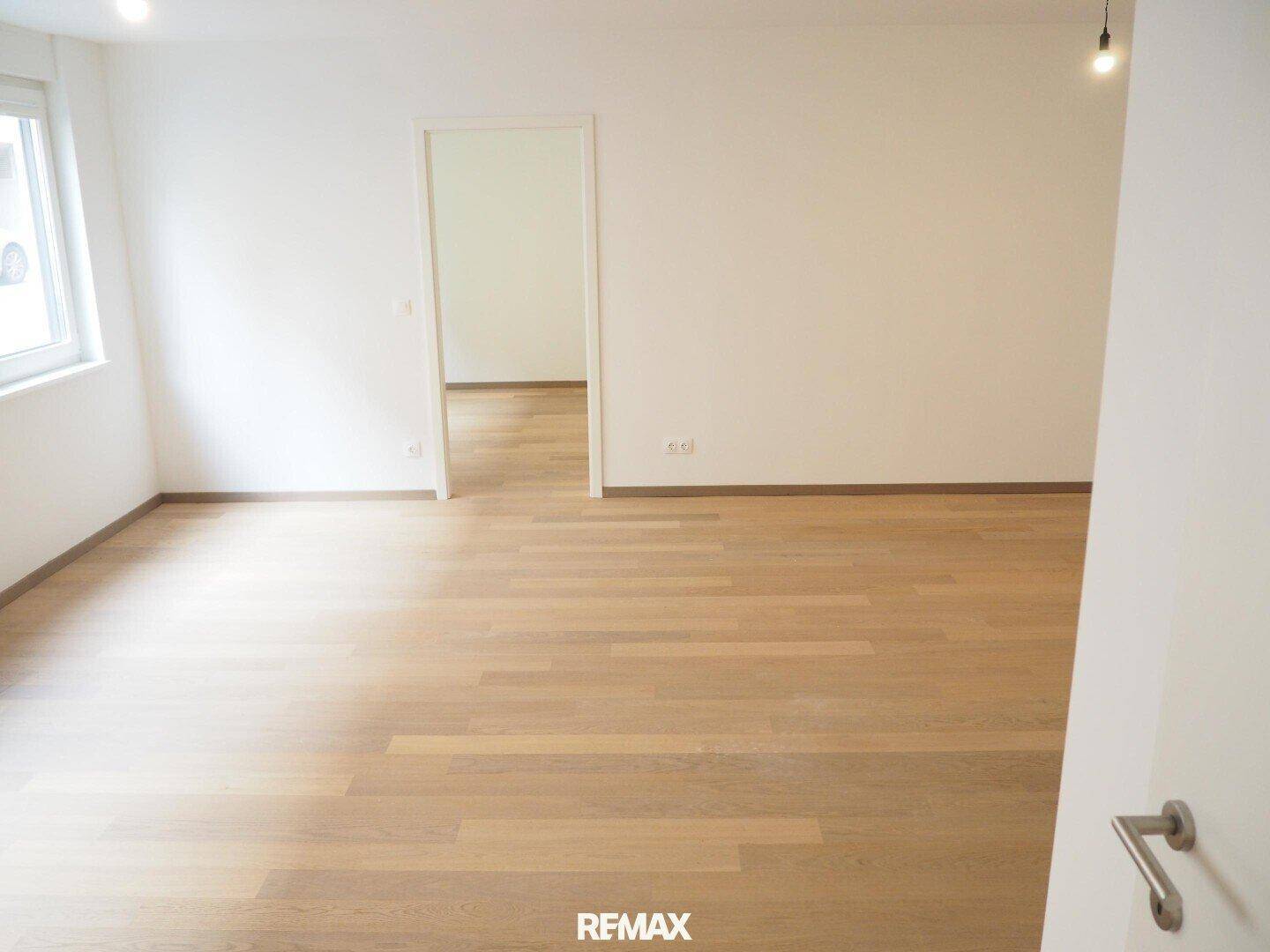 Heller Raum mit Parkettboden und Fenster, das viel Tageslicht hereinlässt.
