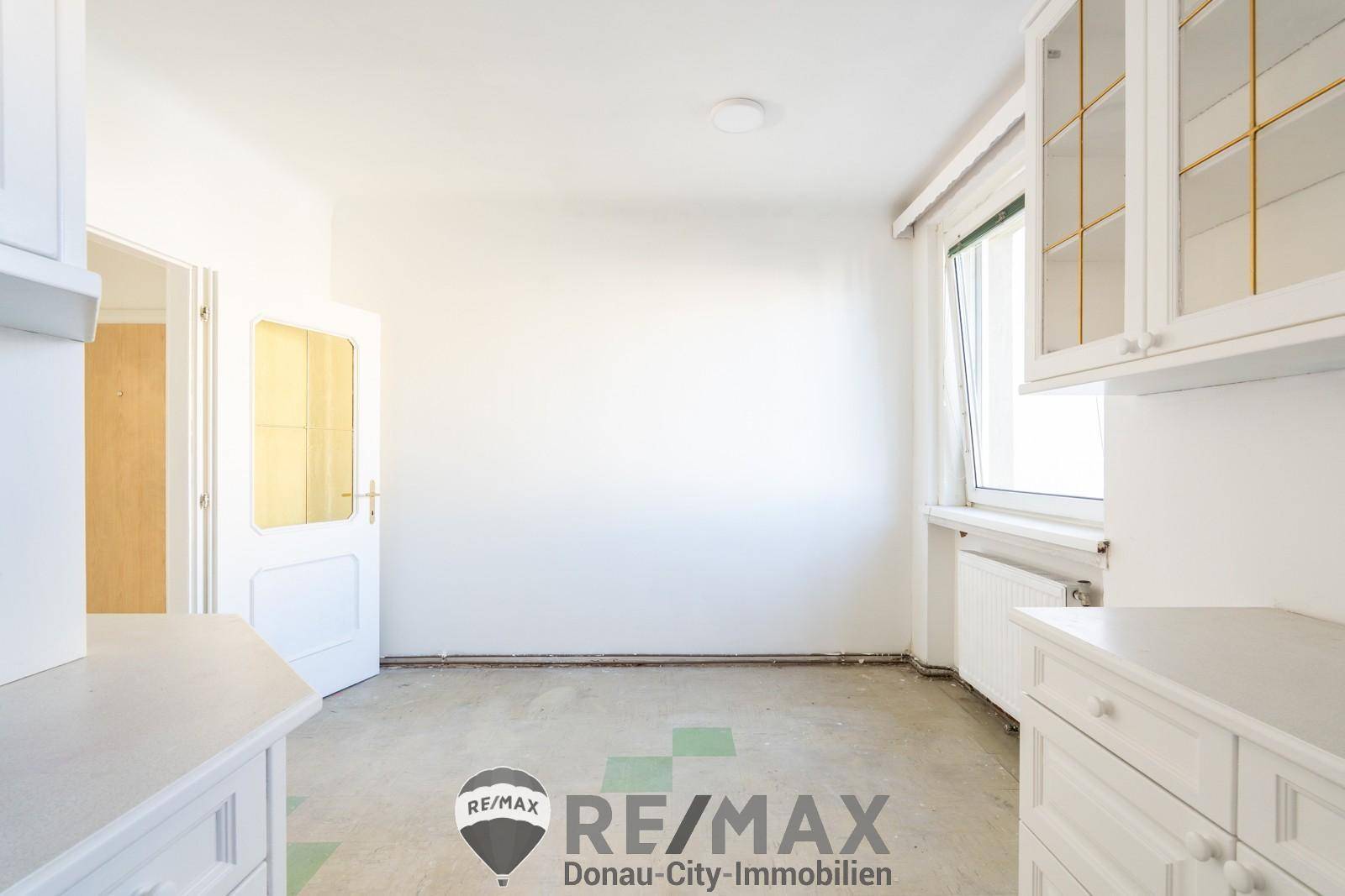 Leerer Essbereich in der Küche mit Fenster und sichtbaren Renovierungsspuren am Boden.