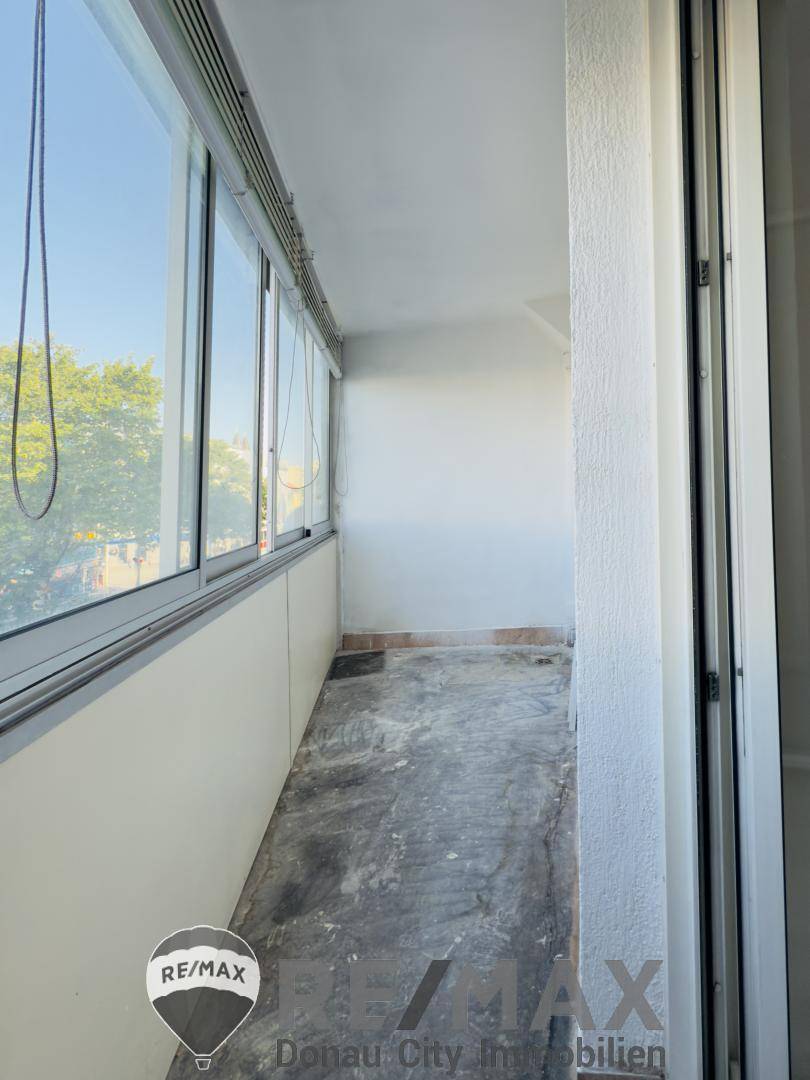 Leerer Balkon mit großen Fenstern, der auf eine Renovierung wartet.