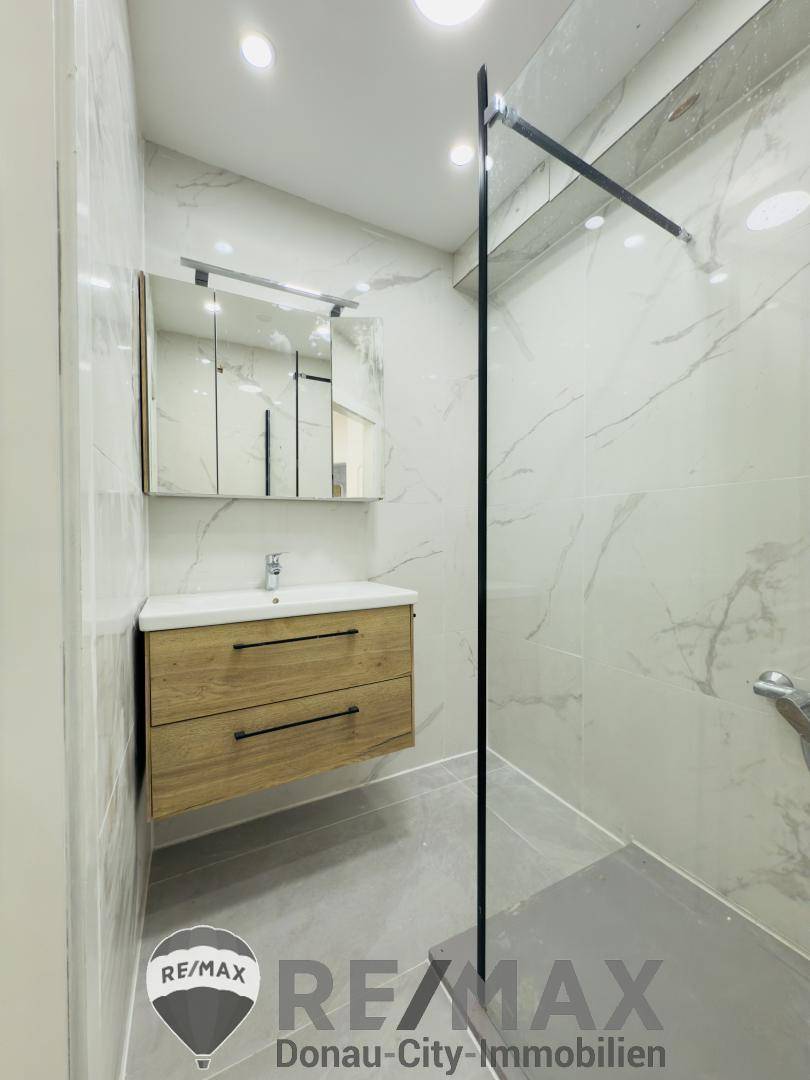 Elegantes Badezimmer mit moderner begehbarer Dusche und stilvollem Waschtischunterschrank.