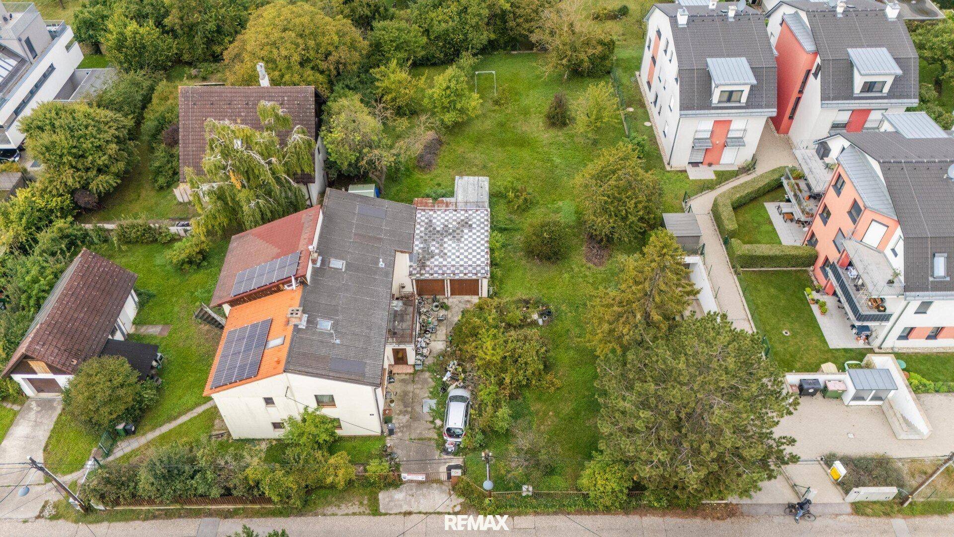 Vogelperspektive des Hauses mit Solaranlagen auf dem Dach und angrenzendem Gartenbereich.