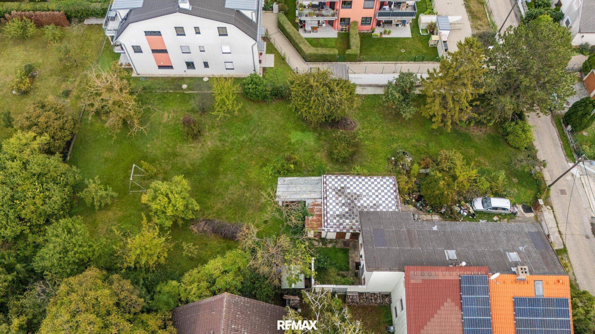 Draufsicht auf das Anwesen mit dem Hauptgebäude und der weitläufigen grünen Gartenfläche.