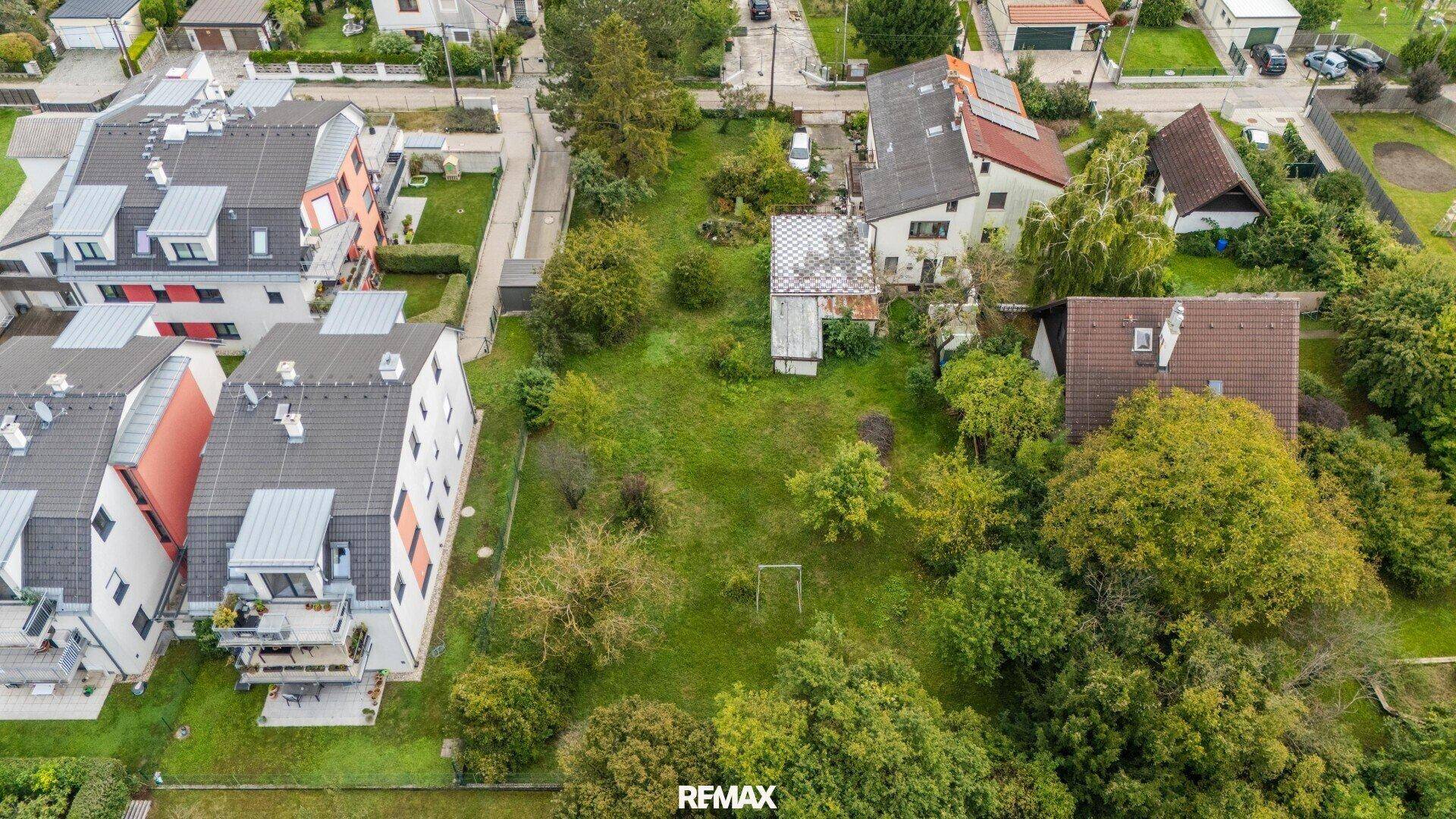 Grundstück mit weißer Umrandung, zeigt ein Haus, viel Grünfläche und benachbarte Gebäude.
