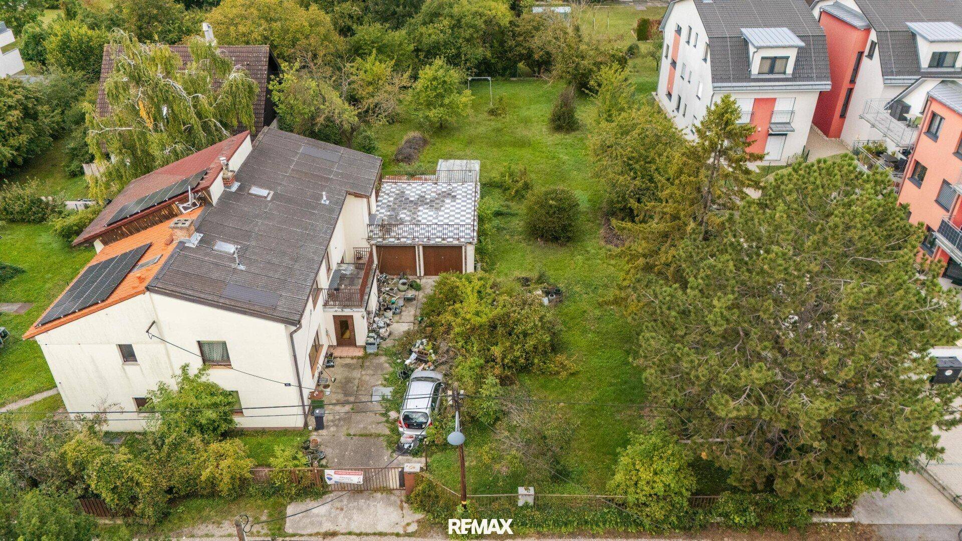 Vorderansicht des Hauses aus der Luft mit Solaranlagen auf dem Dach und dem grünen Grundstück.