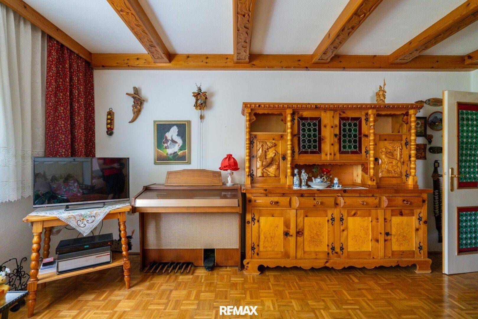Wohnbereich mit traditionellen Holzmöbeln, Holzbalkendecke und Parkettboden, sehr einladend.