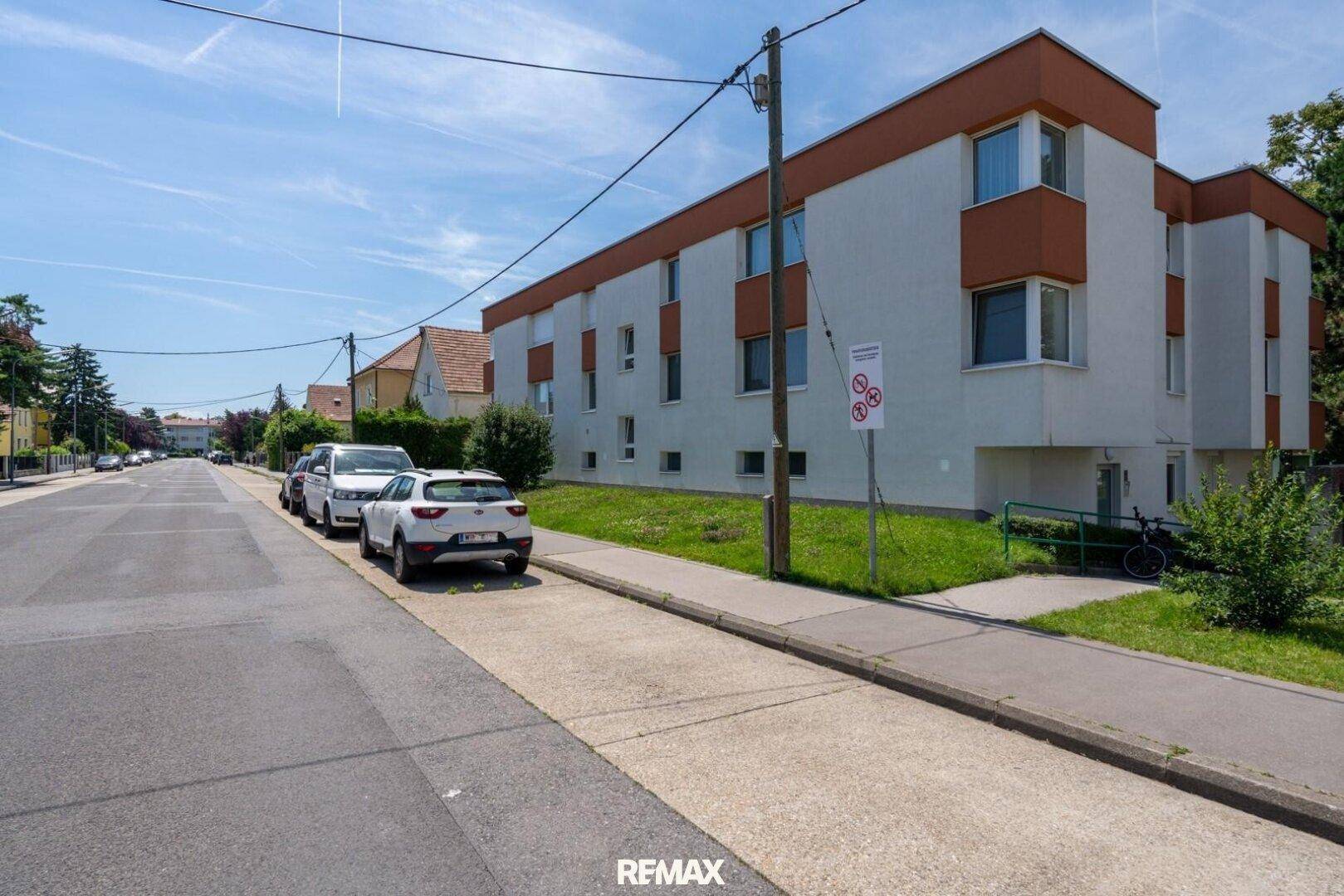 Wohngebäude an einer ruhigen Straße mit geparkten Autos und Grünstreifen, in angenehmer Lage.