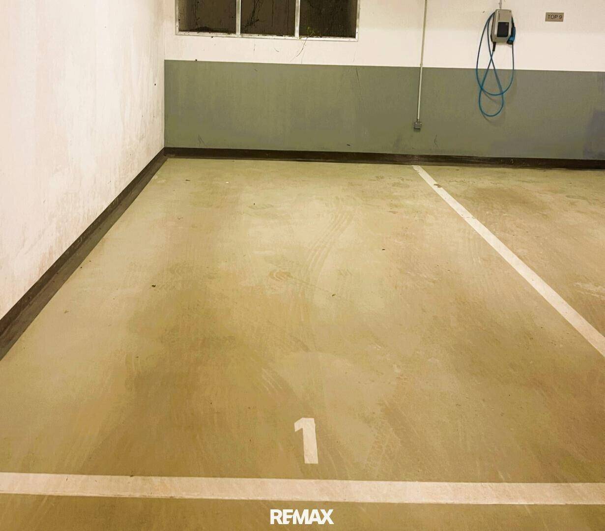 Leerer Tiefgaragenstellplatz Nummer eins mit installierter Ladestation für Elektrofahrzeuge.