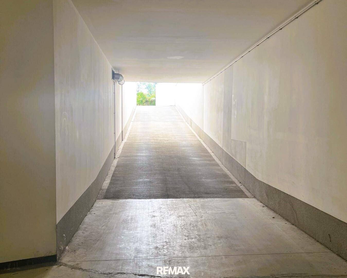 Lange, schmale Tiefgaragenrampe führt zum Tageslicht im Freien.