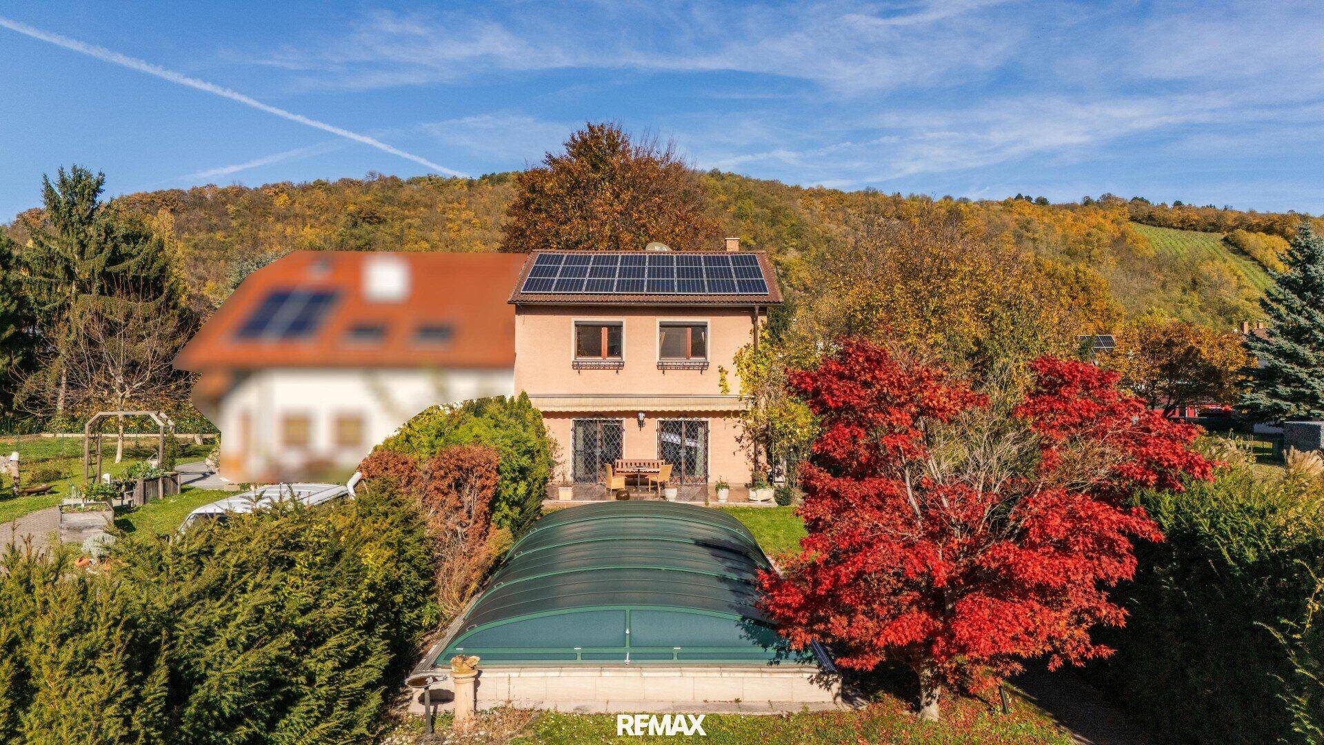 Luftaufnahme des Hauses mit überdachtem Pool, umgeben von Bäumen und Hügeln.