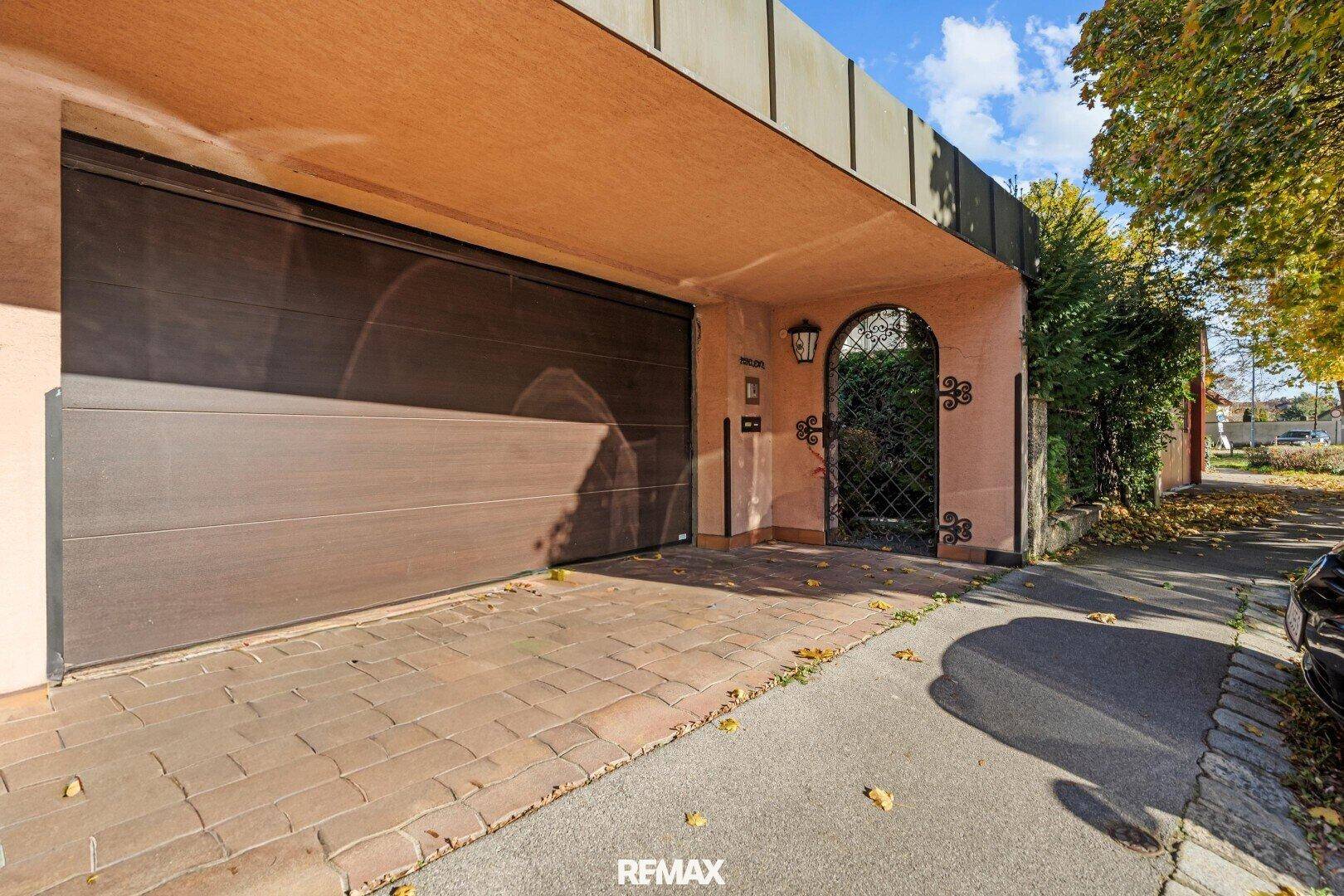 Garage mit großem braunem Tor und einem dekorativen schmiedeeisernen Eingangstor.