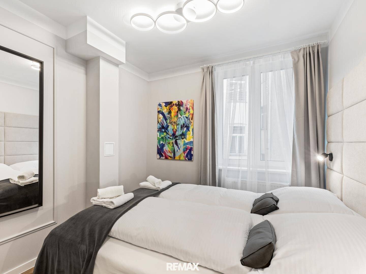 Gemütliches Schlafzimmer mit Doppelbett, Spiegel und moderner Kunst an der Wand.