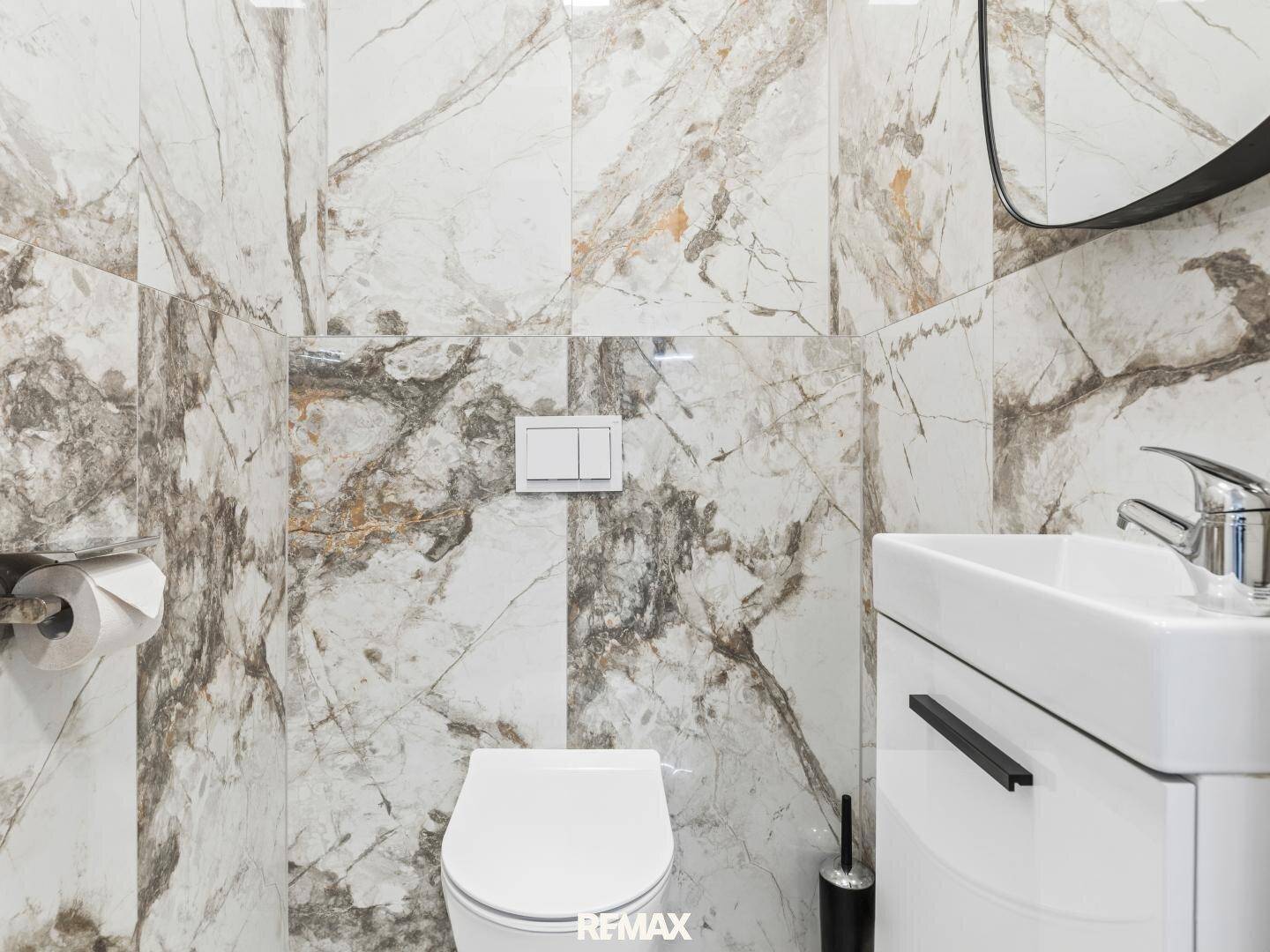 Modernes Gäste-WC mit Wand-WC und Marmorfliesen an den Wänden.