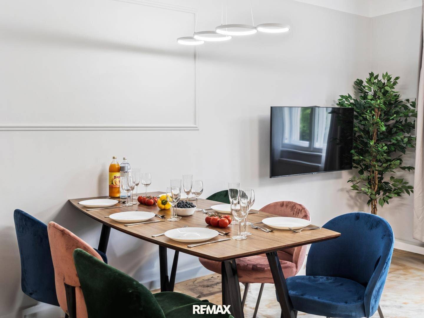 Essbereich mit Holztisch und farbigen Stühlen, ideal für gesellige Mahlzeiten.