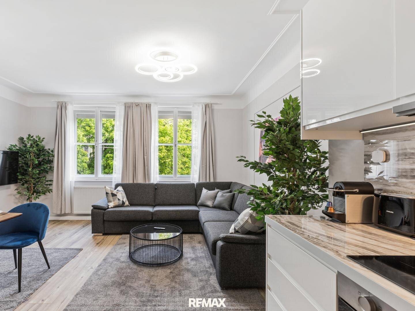 Moderner Wohnbereich mit Ecksofa, Holzboden und Blick ins Grüne.