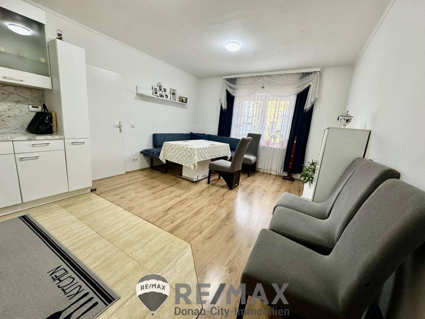 Offener Wohn- und Essbereich mit Laminatboden und einer kleinen Küchenzeile.