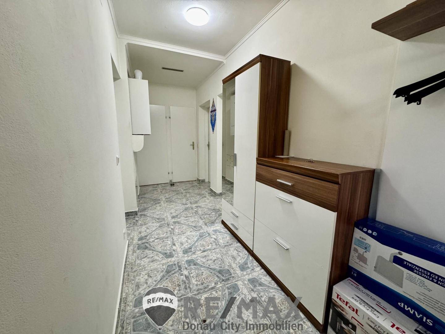 Heller Flur mit gemusterten Fliesen und praktischem Garderobenschrank.