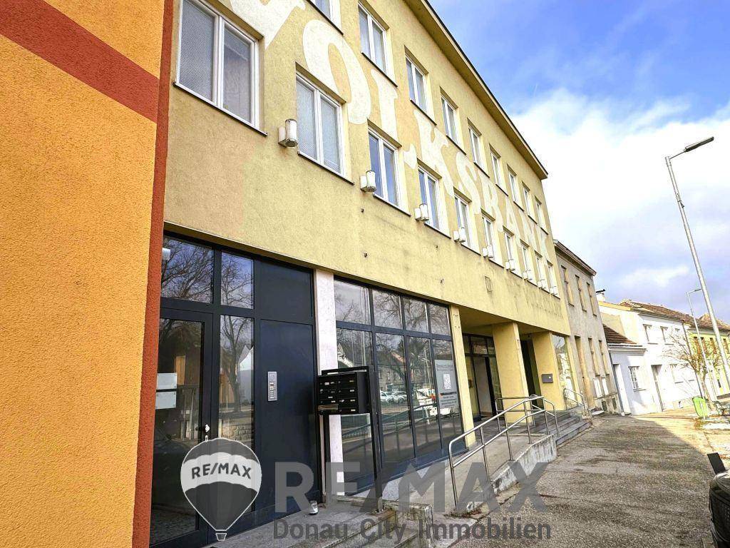 Gelbe Fassade eines Mehrfamilienhauses mit großen Fenstern und barrierefreiem Zugang.