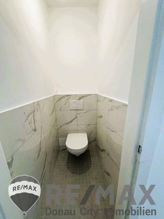 Separate Gästetoilette mit modernen Fliesen und wandmontiertem WC.