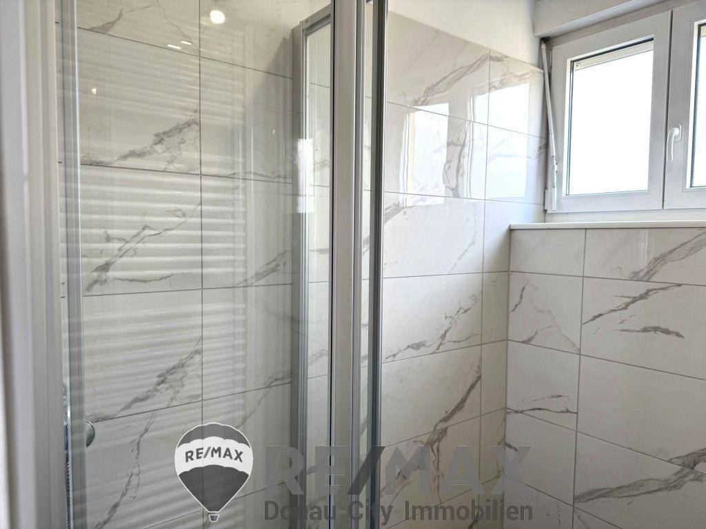 Duschbereich im modernen Badezimmer mit eleganten Marmorfliesen und Glasabtrennung.