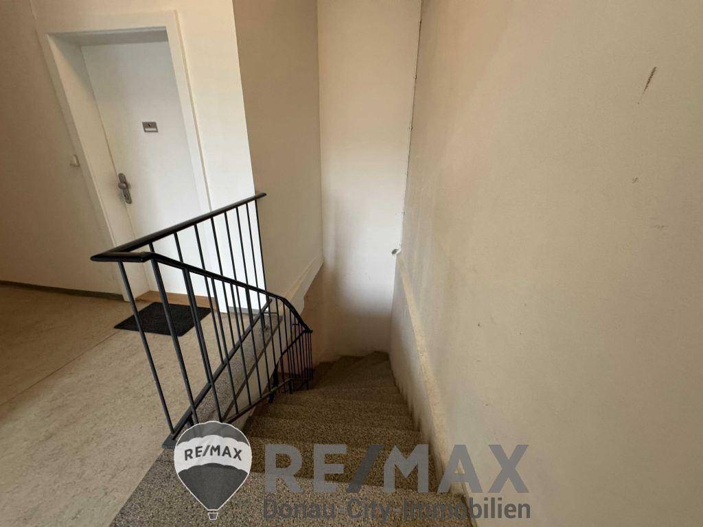 Treppenhaus mit Teppichboden und schlichtem Geländer, das zu den oberen Etagen führt.