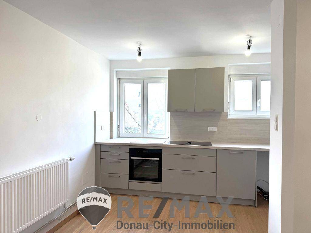 Funktionale Küche mit grauen Schränken, integrierten Geräten und ausreichend Arbeitsfläche.