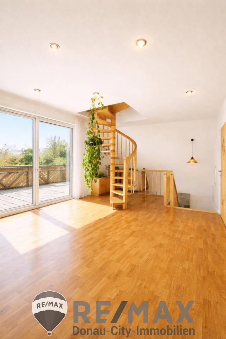 Heller Raum mit Wendeltreppe und großem Schiebetürzugang zu einer Terrasse.
