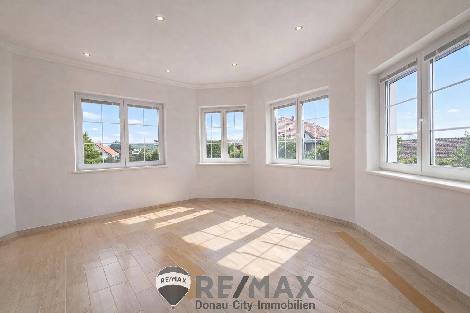 Heller, leerer Raum mit vielen Fenstern und Parkettboden, ideal für individuelle Gestaltung.