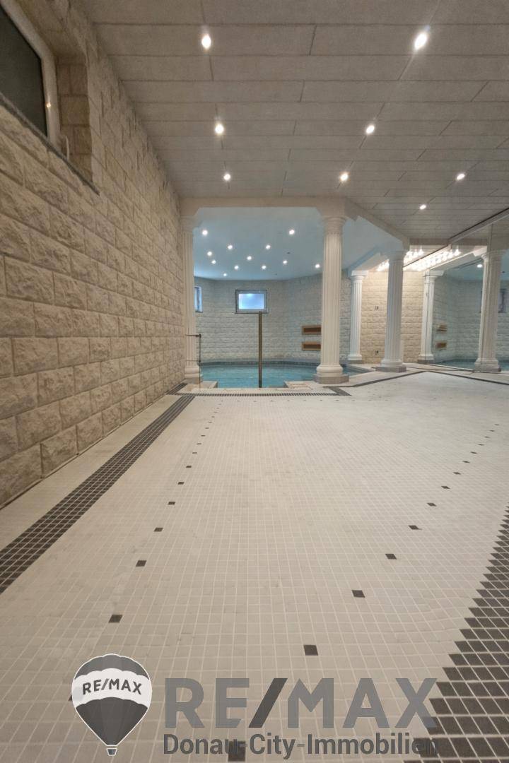 Geräumiger Flurbereich mit Fliesenboden und Blick auf den Innenpoolbereich.