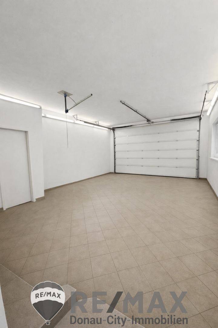 Helle Garage mit Fliesenboden und großem Garagentor, bietet viel Platz.