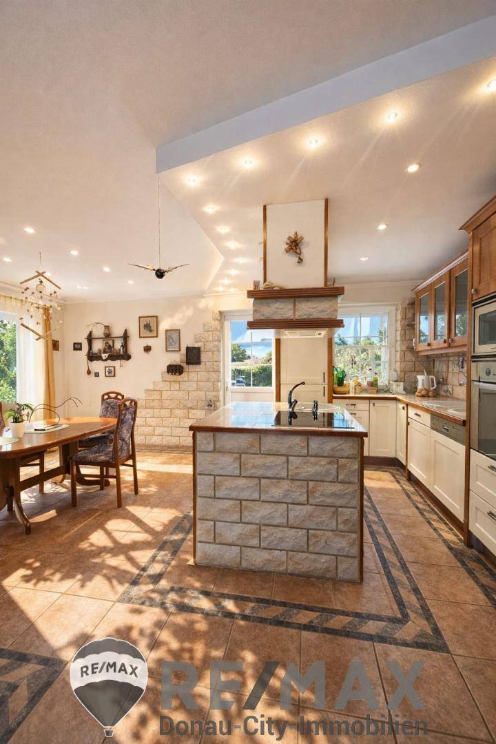 Geräumige Küche mit Essbereich, Kücheninsel und gefliestem Boden, hell und einladend.