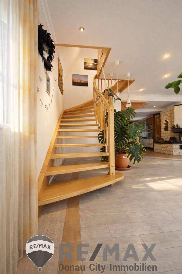 Elegante Holztreppe mit geschwungenem Geländer in einem hellen Eingangsbereich.